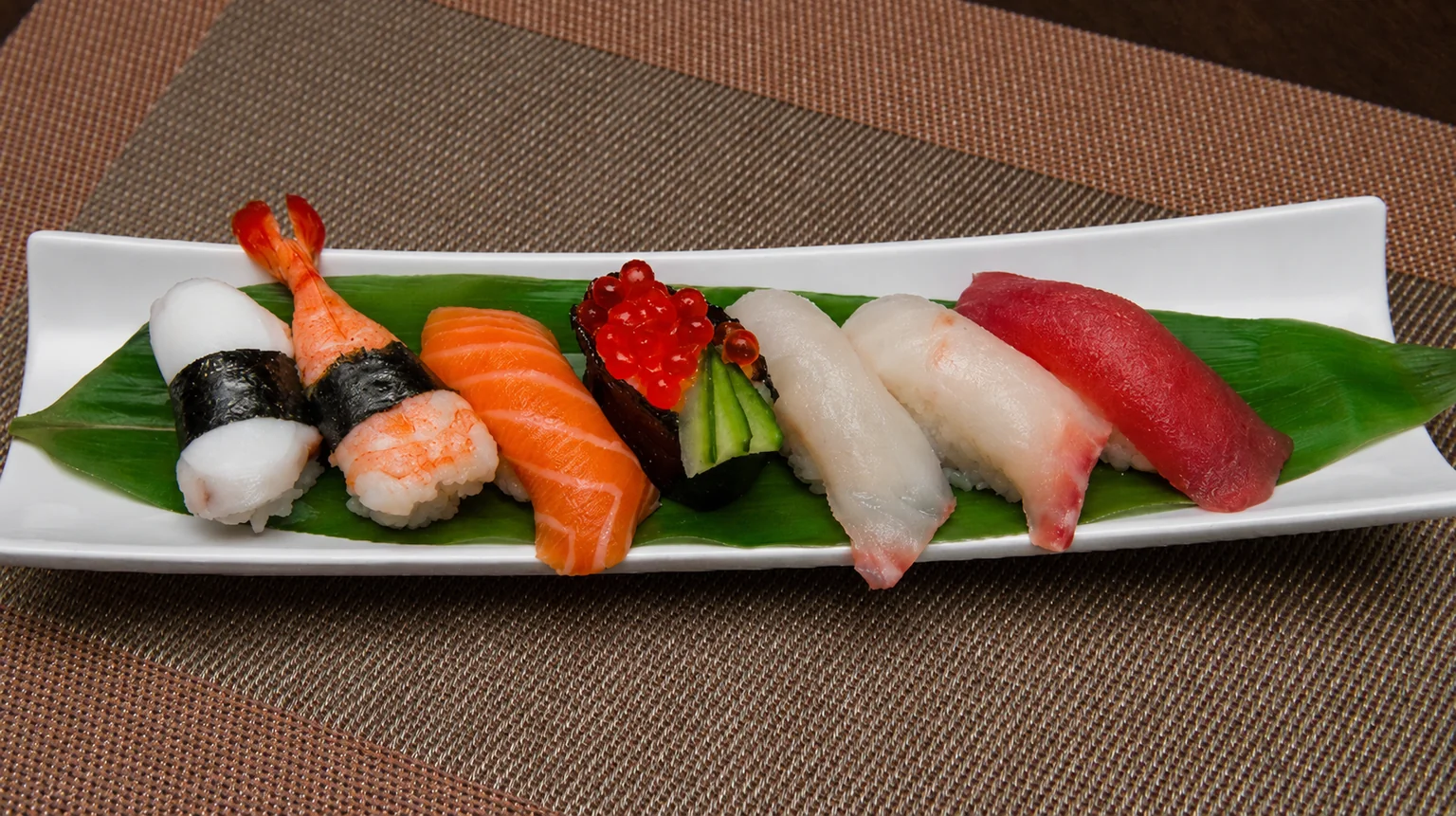 Illustration : Sushi sur une assiette blanche, sur un set de table brun.