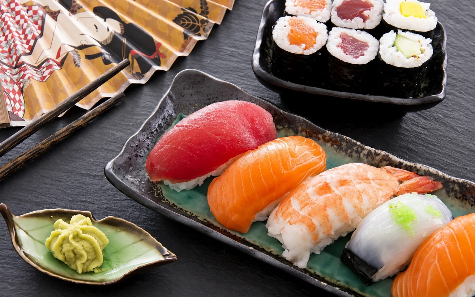 Illustration : Sushi et maki sur des assiettes noires.